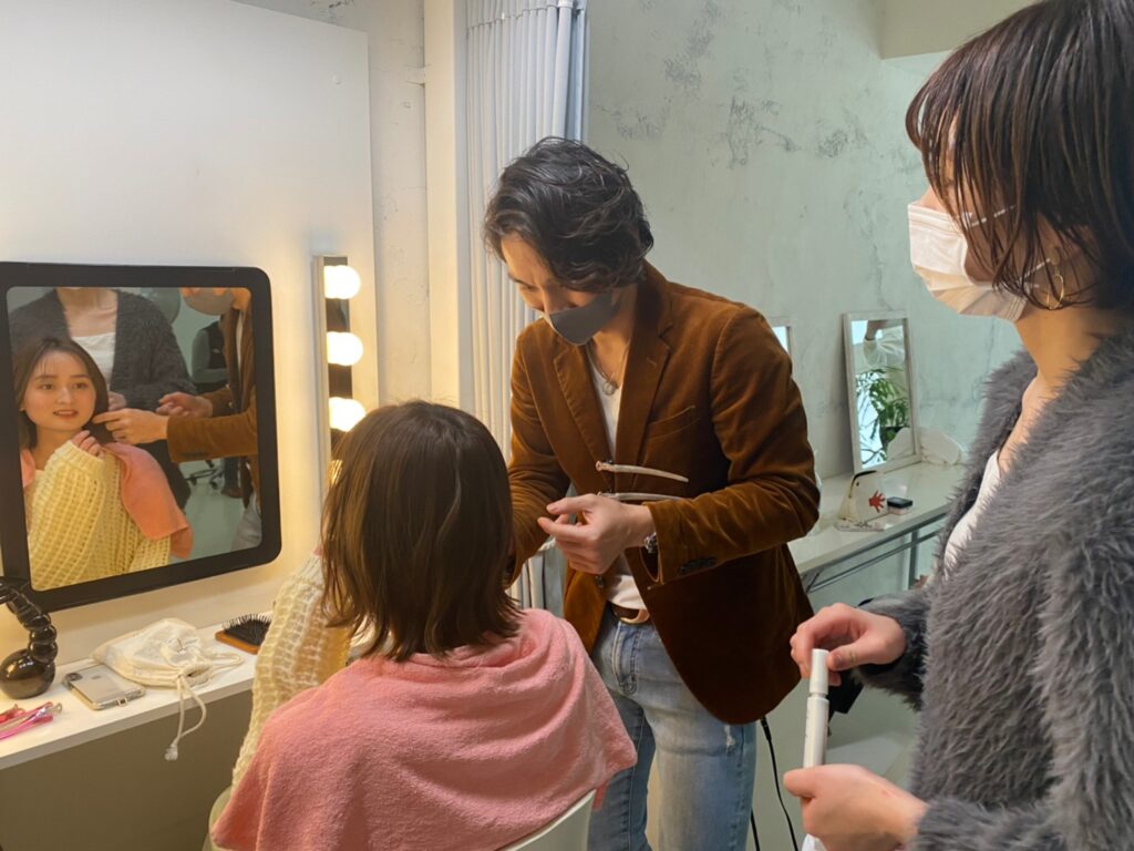 スタジオでモデルさんのヘアスタイルをセットする笹田賢司